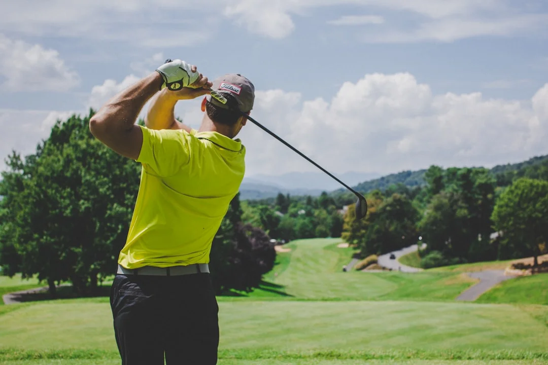 A performance-minded golfer reviewing launch monitor data on a tablet beside a driver and iron set on a grass range tee